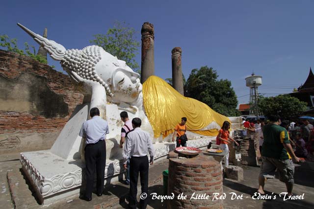 Worshippers paste gold leaf onto the Buddha.