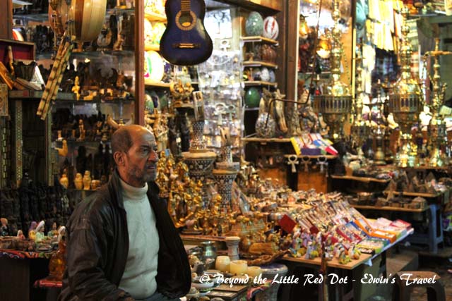 A shopkeeper sitting in front of his shop.