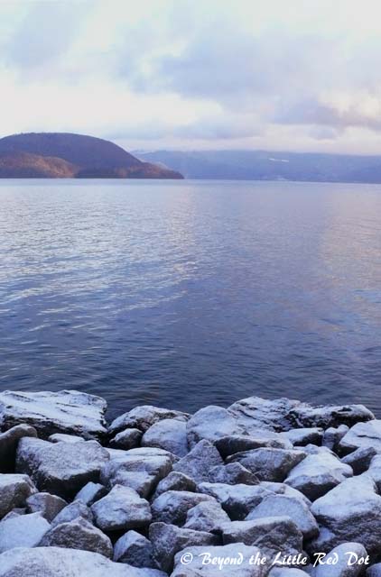 Snow frosted rocks and Lake Toya in the background.