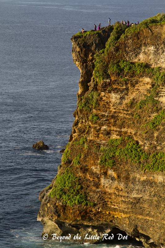 More tourists risking their lives taking selfiies by the cliff edge.