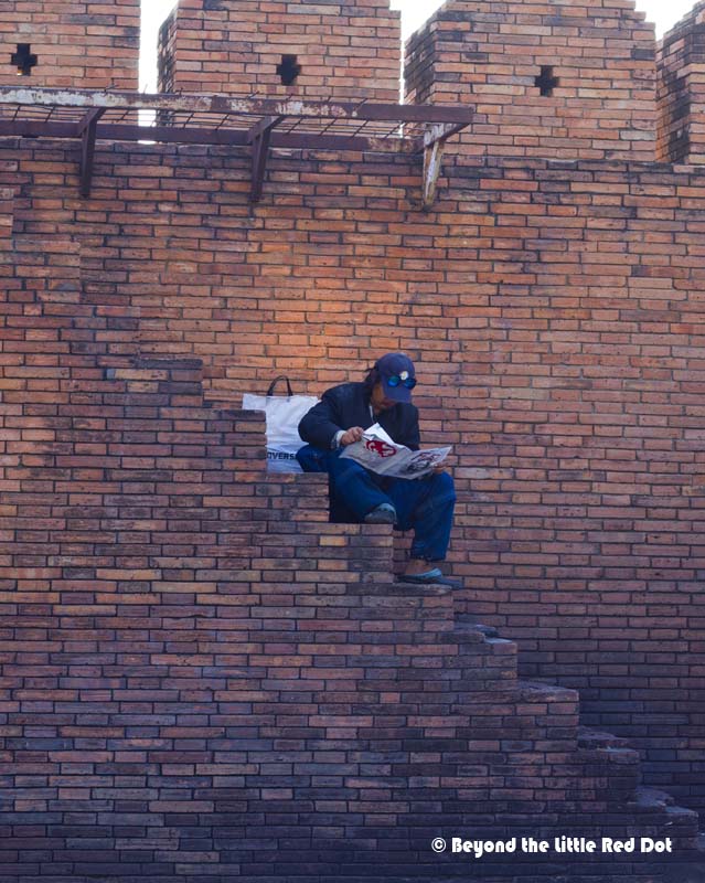 Reading the morning news on the steps of Ta Phae Gate.