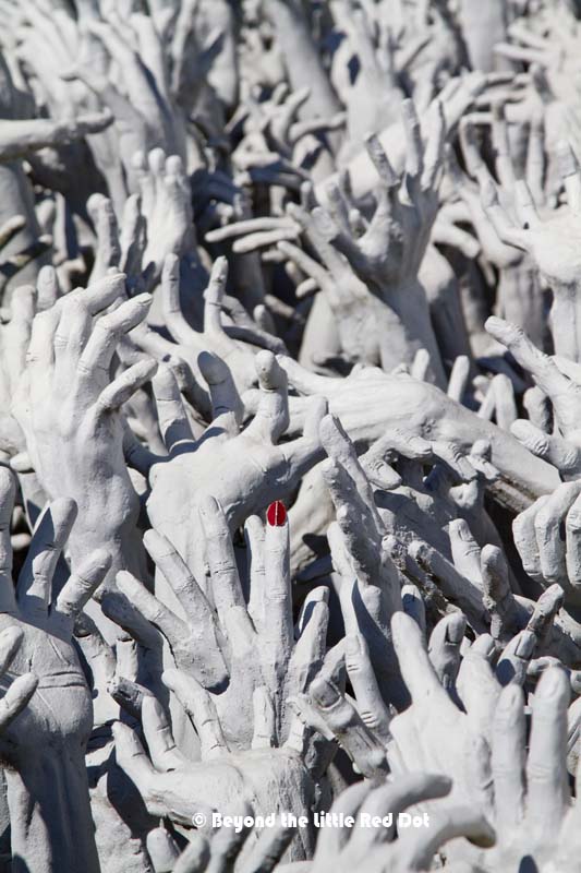 Look for the hand with the red fingernail. It's also giving you the finger at the same time. The artist's humor at work.